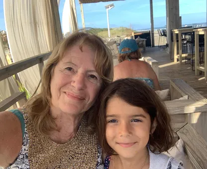 A grandmother and her granddaughter taking a selfie on a beach terrace
