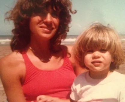 An old family photo of a mother holding her little son on the beach